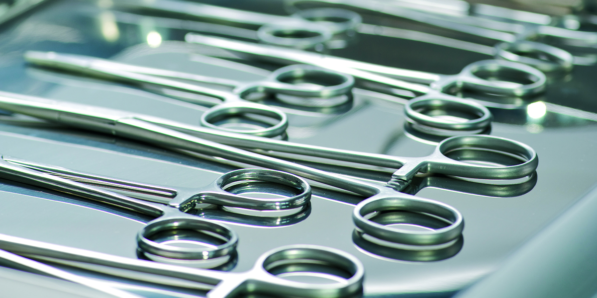 Sterile forceps laid out on a sterile metal tray prepared for surgery.